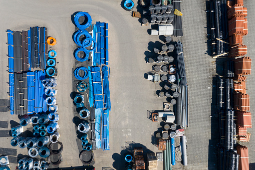 PVC plastic pipes for underground water supply and water meter covers viewed from above at a depot.