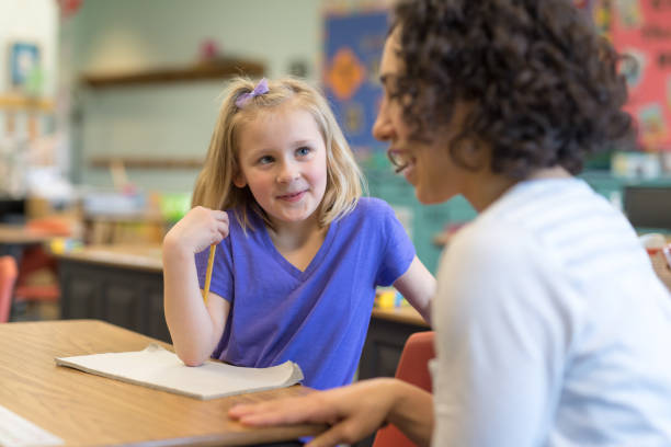 istock First grade girl talking with her teacher in the classroom 1152726146