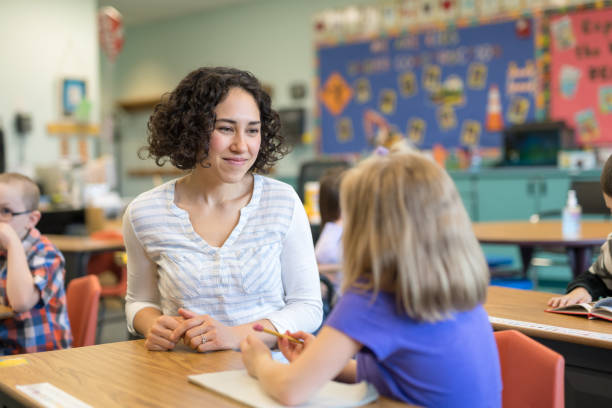 A first grade teacher talking with one of her students in the classroom