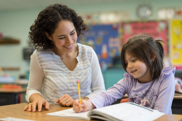 istock First grade girl talking with her teacher in the classroom 1152726162