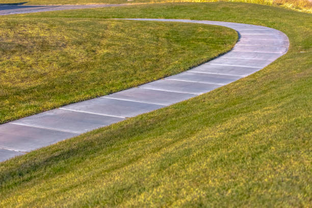 istock Paved footpath that curves through the grassy terrain viewed on a sunny day 1152743979
