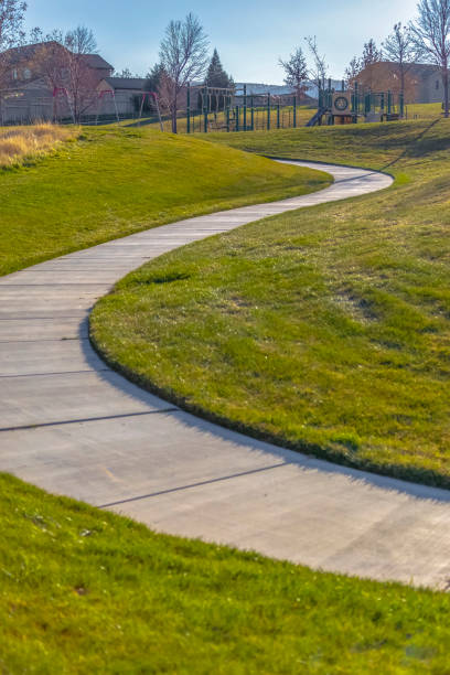 istock Walkway that winds through a rich grassy field at a park with playground 1152743981