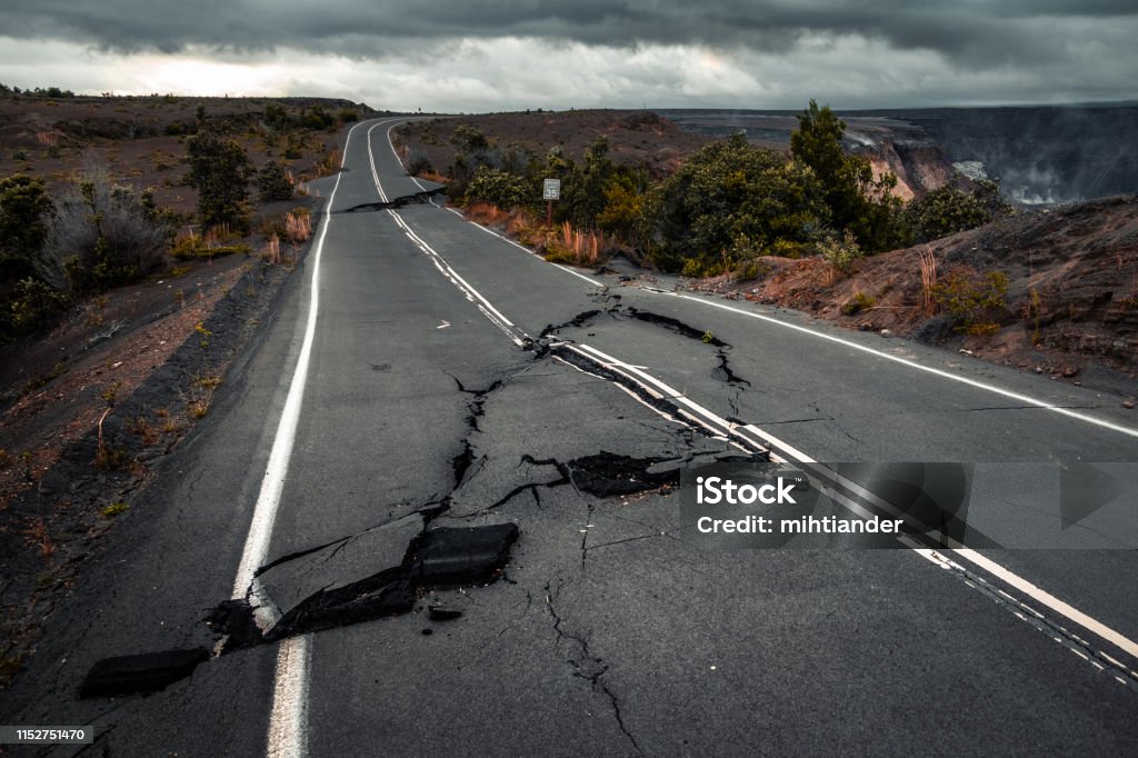 Damaged asphalt road Damaged asphalt road (Crater Rim Drive) in the Hawaii Volcanoes National Park after earthquake and eruption of Kilauea (fume at upper right) volcano in May 2018. Big Island, Hawaii Earthquake Stock Photo