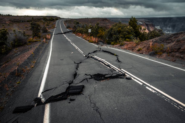 Damaged asphalt road Damaged asphalt road (Crater Rim Drive) in the Hawaii Volcanoes National Park after earthquake and eruption of Kilauea (fume at upper right) volcano in May 2018. Big Island, Hawaii hawaii volcanoes national park photos stock pictures, royalty-free photos & images