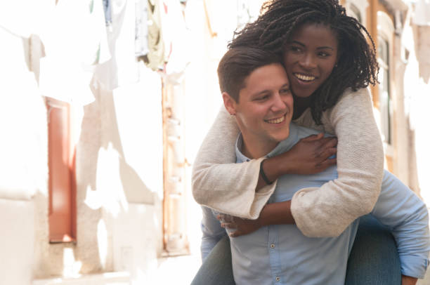 istock Playful guy carrying pretty girlfriend on back outdoors 1152753845