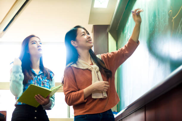 istock young student explain to her friend on how to solve the question on the blackboard 1152755870