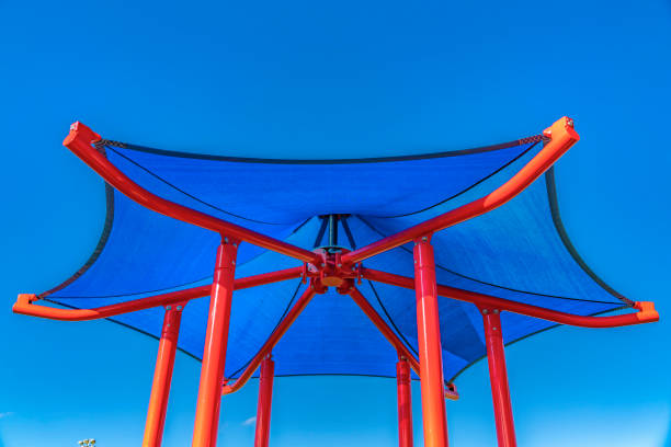 Hexagon shaped blue roof supported by red poles against vibrant sky. Details of the tower of a playground equipment on a sunny day.