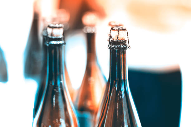 Several glass bottles of champagne with stoppers. Tube holding the wire. The background is blurred.