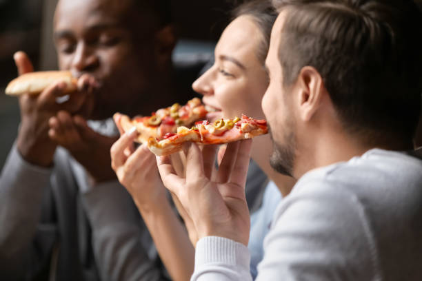 fermez-vous heureux divers amis mangeant la pizza dans le café ensemble - bon appetite photos et images de collection