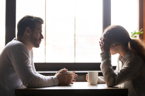 Upset woman and man talking in cafe about relationships Upset woman and man talking in cafe about problem in relationships, frustrated girlfriend hiding face in hands, couple sitting at table in coffeehouse together, drinking coffee, bad first date couple on bad date stock pictures, royalty-free photos & images