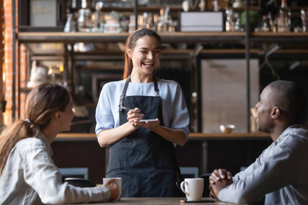 attractive waitress laughing at african american man joke, serving customers - friendship cafe social gathering talking imagens e fotografias de stock