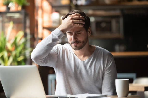 istock Upset man working in cafe, suffering from headache, touching forehead 1152767894