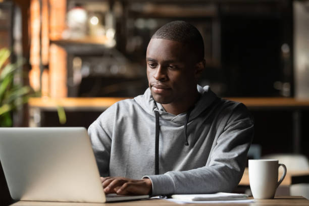 istock African American man using laptop in cafe, looking at screen 1152767897
