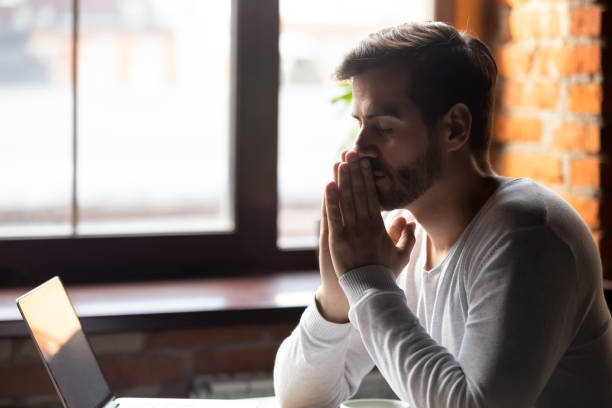 istock Worried man thinking about problem puts hands together in prayer 1152767900