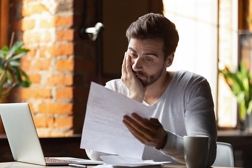 Confundido hombre frustrado leyendo carta en el café, recibiendo malas noticias photo