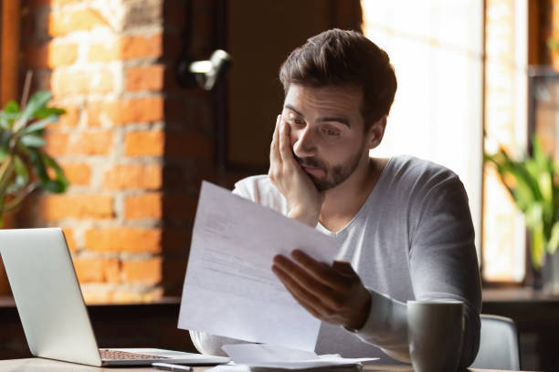 Confused frustrated man reading letter in cafe, receiving bad news Confused frustrated young man reading letter in cafe, debt notification, bad financial report, money problem, money problem, upset student receiving bad news, unsuccessful exam or test results frustration stock pictures, royalty-free photos & images