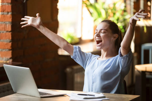 istock Excited smiling woman celebrating online win, using laptop in cafe 1152767906