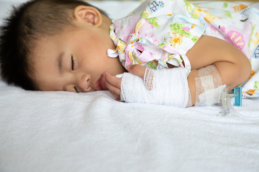 Niño Asiático durmiendo en la cama con infusión en el Departamento de niños en el hospital. Niños con enfermedades infecciosas IPD, concepto de enfermedad neumocócica invasiva. Modelo infantil un año seis meses photo