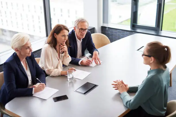 Woman during job interview and three elegant members of management