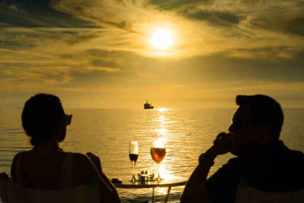 Mykonos, Greece - May 12, 2019: Couple enjoying drinks observing the sunset at Little Venice in Mykonos town (Chora), Mykonos island, Cyclades, Greece.