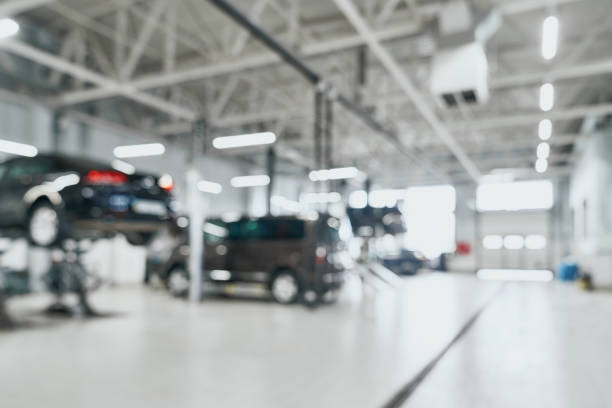 station service de réparation avec des voitures modernes levées étant sous maintenance et techniciens sur fond flou avec de nombreuses lampes à diodes. concept de service et de technicien automobile - auto repair shop photos et images de collection