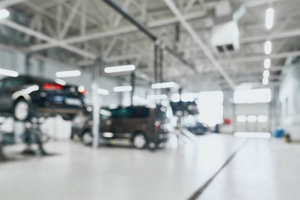 Repair service station with lifted modern cars being under maintenance and technicians on blurred background with many diode lamps. Auto service and technician concept stock photo