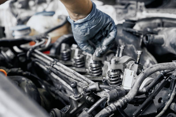 close up of nozzles in car diesel engine with mechanic's hand in blue dirty rubber gloves doing professional auto repairing. engine maintenance concept - vela de ignição imagens e fotografias de stock