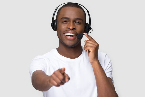 istock Smiling african man in headset looking pointing finger at camera 1152782369