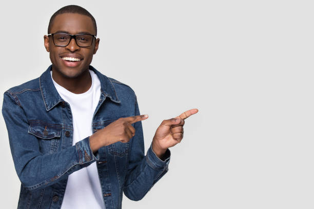 istock Smiling african man wearing glasses looking at camera pointing aside 1152782378