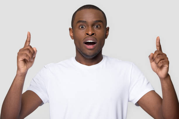 istock African guy open mouth feels amazed pointing fingers up 1152782390