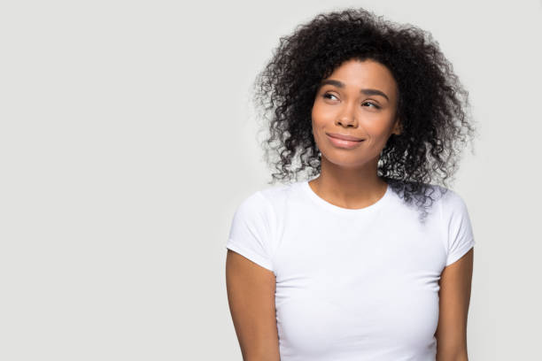 istock Dreamy african girl pose aside over grey blank background 1152782417