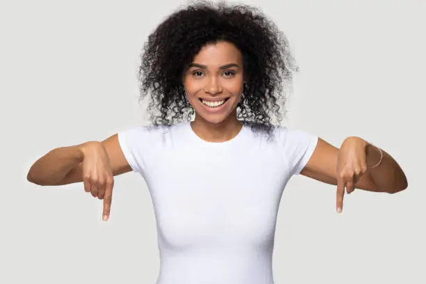 Photo of African woman isolated on grey blank pointing fingers down