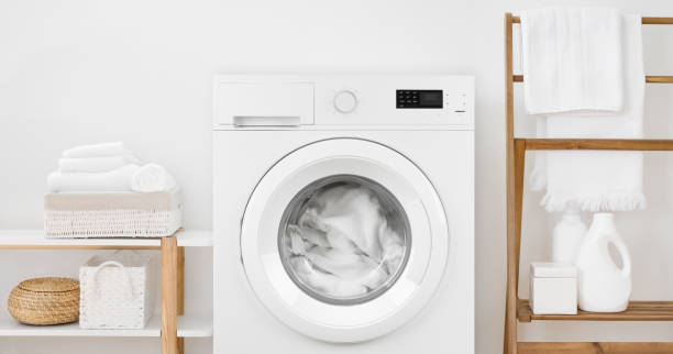 istock Washing machine with laundry and shelves on white wall background 1152783220