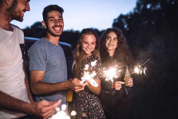 grupa przyjaciół z iskierkami stojącymi na zewnątrz o zmierzchu. - travel adolescence road trip outdoors zdjęcia i obrazy z banku zdjęć