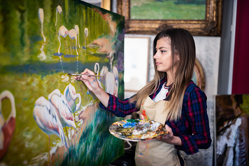 Portrait of young beautiful female artist painter in studio.