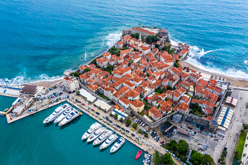 High angle view of Old Town of Budva standing on top of Fortress Mogren, and a marine with some yachts behind it.