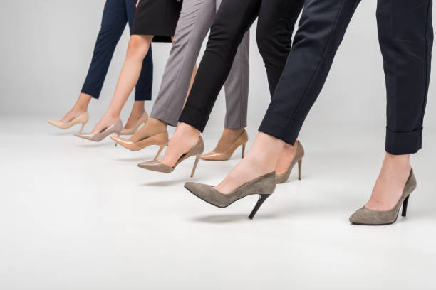 cropped view of businesswomen walking in high heel shoes on grey background cropped view of businesswomen walking in high heel shoes on grey background women high heels stock pictures, royalty-free photos & images