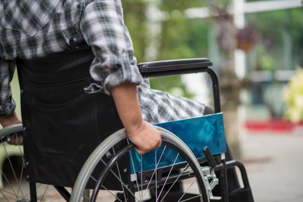 Close-up of senior woman hand on wheel of wheelchair during walk in hospital stock photo