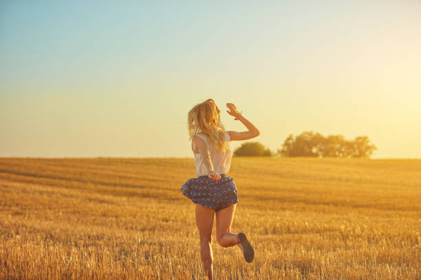 Cute young woman jumping in a wheat field.