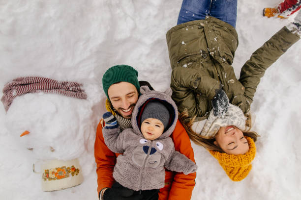 Posing with our Snowman Portrait of a little boy and his parents proudly posing with a Snowman they have made together coat garment photos stock pictures, royalty-free photos & images