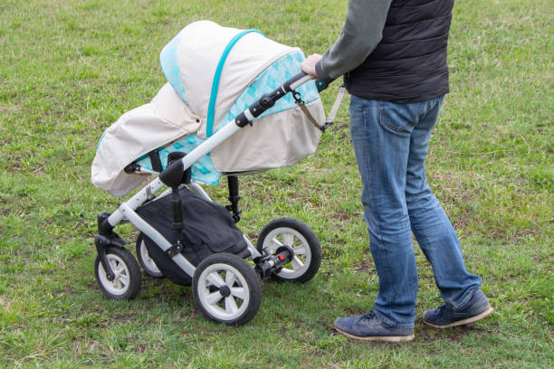 istock father walks with carriage, bottom view only legs. Bright mint stroller and legs in jeans, walking with a child outdoor 1152808433