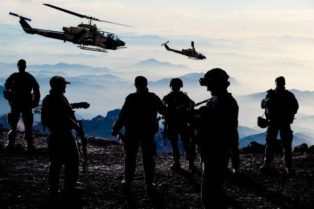 silhouetten der soldaten während der militärmission in der abenddämmerung - battlefield stock-fotos und bilder