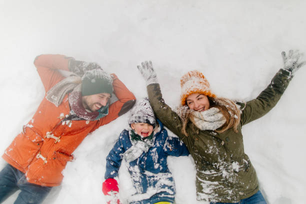 Making snow angels Photo of a boy and his parents making snow angels in the snow snow angels stock pictures, royalty-free photos & images
