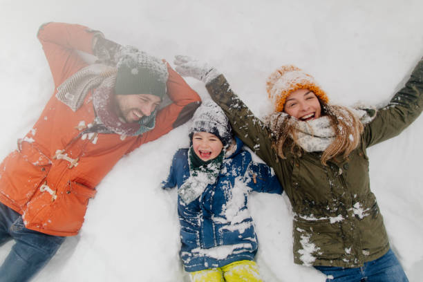 making snow angels - offspring child lying on back parent imagens e fotografias de stock