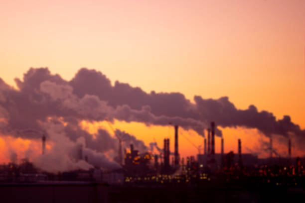 Blurred industrial landscape. Violet smoke from the pipes at sunset on the outskirts of the city. Environmental problems and air pollution