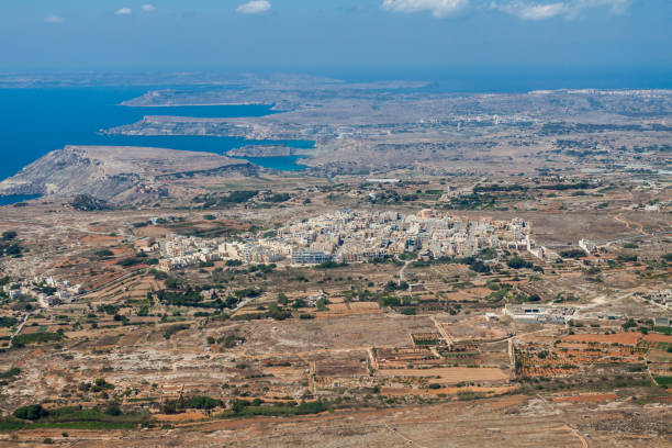 Aerial view of L-Imgarr, Mgarr, or Mgiarro town, Northern region, Malta island. Rich farmland and vineyards around. Panoramic photo of Malta from above toward north-west and Gozo island Aerial view of L-Imgarr, Mgarr, or Mgiarro town, Northern region, Malta island. Rich farmland and vineyards around. Panoramic photo of Malta from above toward north-west and Gozo island. mgarr malta island gozo cityscape with harbor stock pictures, royalty-free photos & images