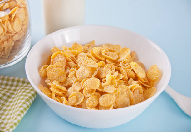 istock A bowl of dry corn flakes cereal on blue background 1152813886