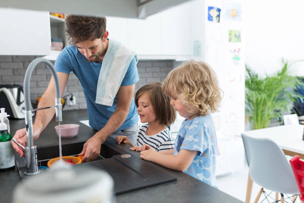 istock Father and sons washing dishes together 1152817539
