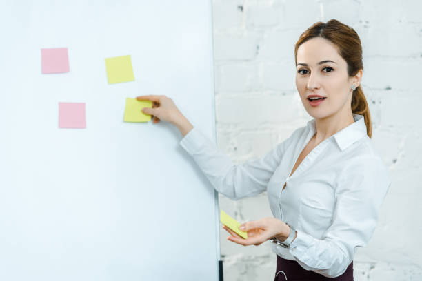 istock attractive business coach putting sticky notes on white board 1152819243