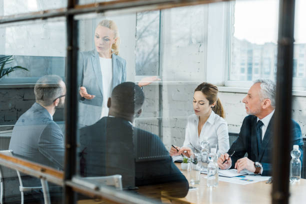 istock selective focus of business coach talking while gesturing in conference room near multicultural coworkers 1152820717